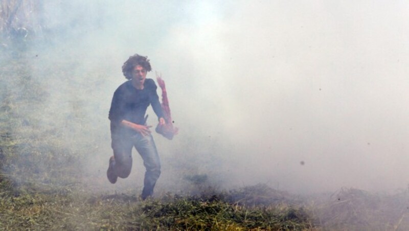 Ein Flüchtling versucht in Idomeni dem Tränengas zu entkommen. (Bild: AP)