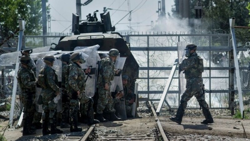 Mazedonische Grenzpolizisten gehen vor Steinwürfen in Deckung. (Bild: APA/AFP/ROBERT ATANASOVSKI)