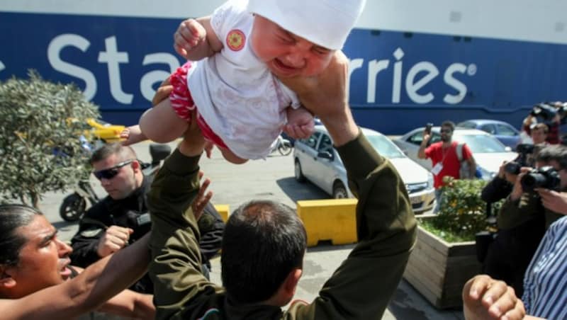 Das Baby weint bitterlich, als es der Mann über seinen Kopf hält. (Bild: AP)