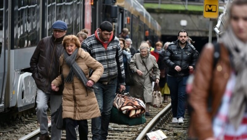 Fahrgäste verlassen nach Aufforderung der Polizei die Straßenbahn. (Bild: APA/AFP/PATRIK STOLLARZ)