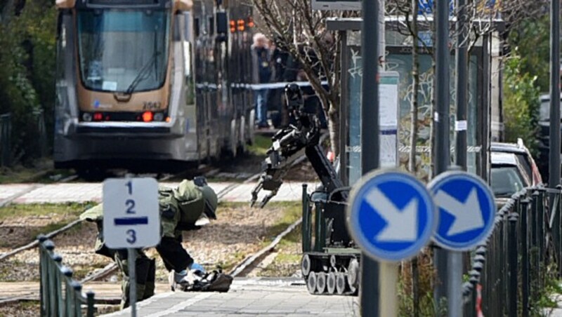 Vorsichtig wird der Rucksack des Verhafteten in der Straßenbahnhaltestelle inspiziert. (Bild: APA/AFP/PATRIK STOLLARZ)