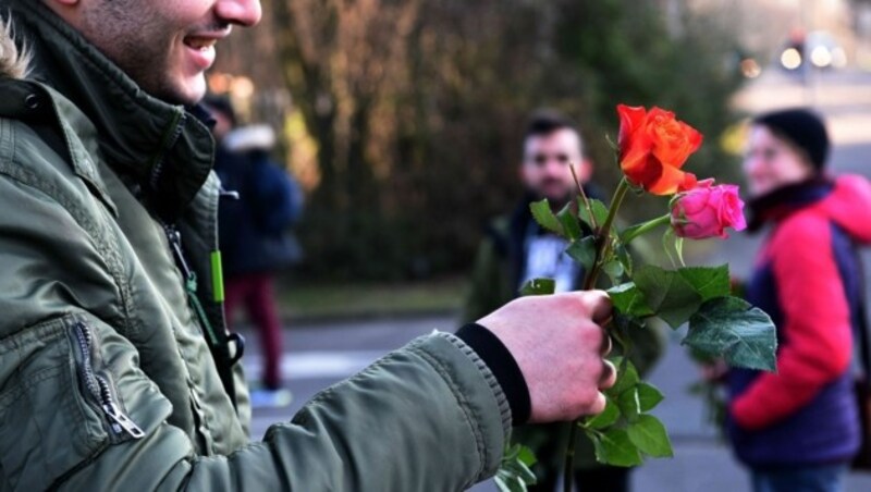 Nach den Ereignissen in der Kölner Silvesternacht verteilt ein Flüchtling Blumen. (Bild: APA/AFP/PATRIK STOLLARZ)