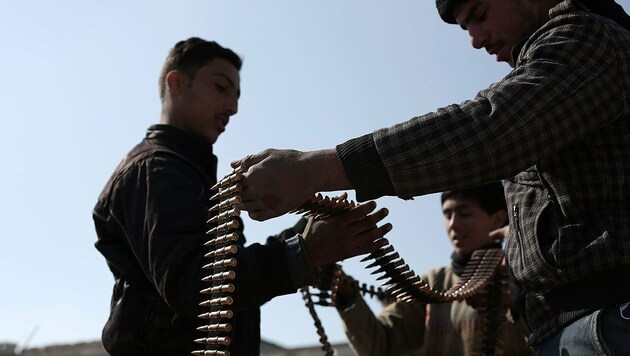 Syrische Rebellen bei der Überprüfung eines Munitionsgurtes (Bild: APA/AFP/AMER ALMOHIBANY)