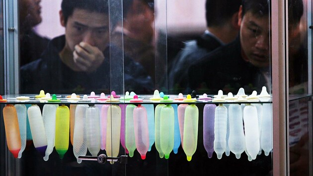 Besucher der Pekinger Messe für Familienplanung vor ausgestellten Kondomen (Bild: STR/AFP/picturedesk.com)