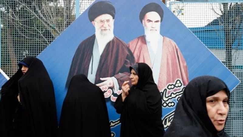 Frauen vor einem Bild von "Perser-Papst" Ali Khamenei und dessen Vorgänger Ayatollah Khomeini (Bild: EPA)