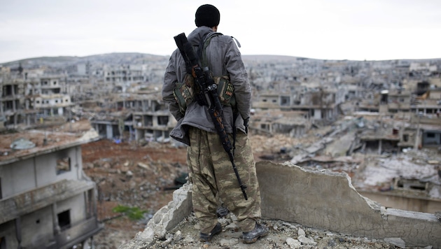 Ein kurdischer Scharfschütze blickt auf die Ruinen der syrischen Grenzstadt Kobane. (Bild: AP)