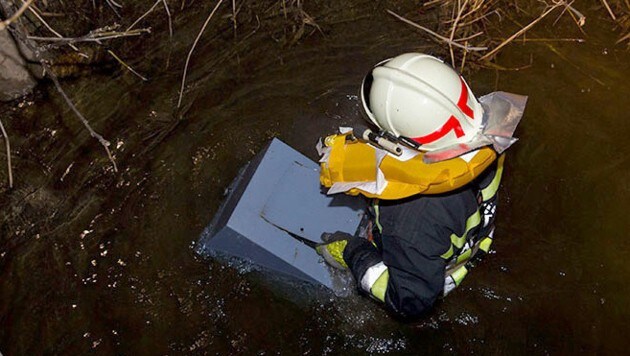 Ein Feuerwehrmann holte den Safe aus dem Bachbett. (Bild: APA/BFK BADEN/STEFAN SCHNEIDER)