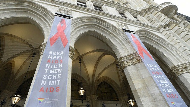 Die "Red Ribbon"-Schleife wurde als sichtbares Symbol der Solidarität am Wiener Rathaus angebracht. (Bild: APA/HELMUT FOHRINGER)