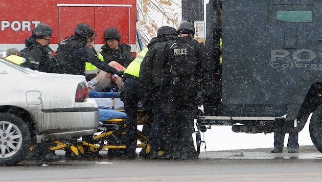 Polizisten bringen einen Verletzten in Sicherheit. (Bild: AP)