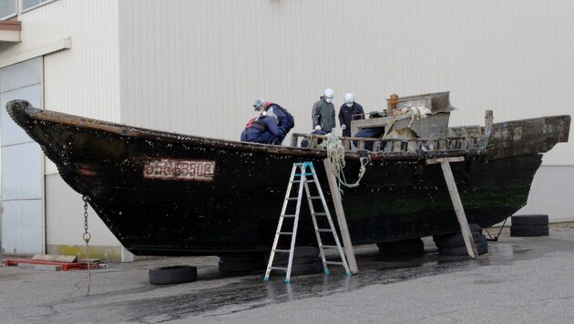 Mitarbeiter der Küstenwache untersuchen in der Stadt Sakai eines der Fischerboote. (Bild: APA/AFP/Jiji Press)