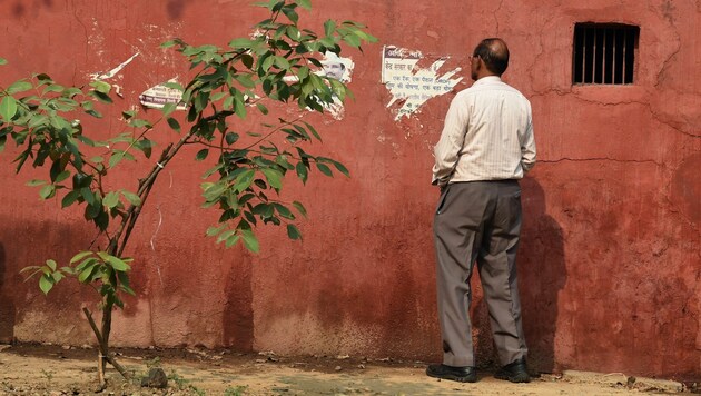 Ein Mann in Mumbai erleichtert sich an einer Hauswand. (Bild: APA/AFP/Sajjad Hussain)
