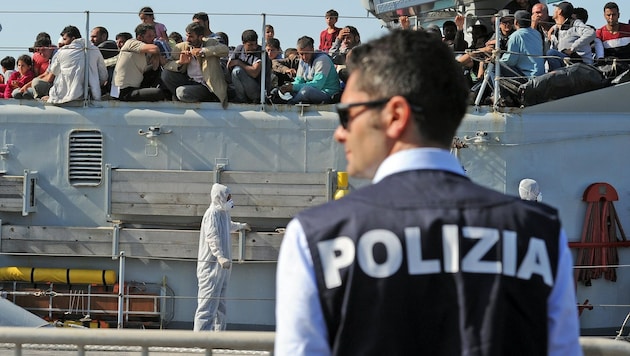 Ein italienischer Polizist wartet auf die Ankunft von Flüchtlingen in Sizilien. (Bild: APA/AFP/GIOVANNI ISOLINO)
