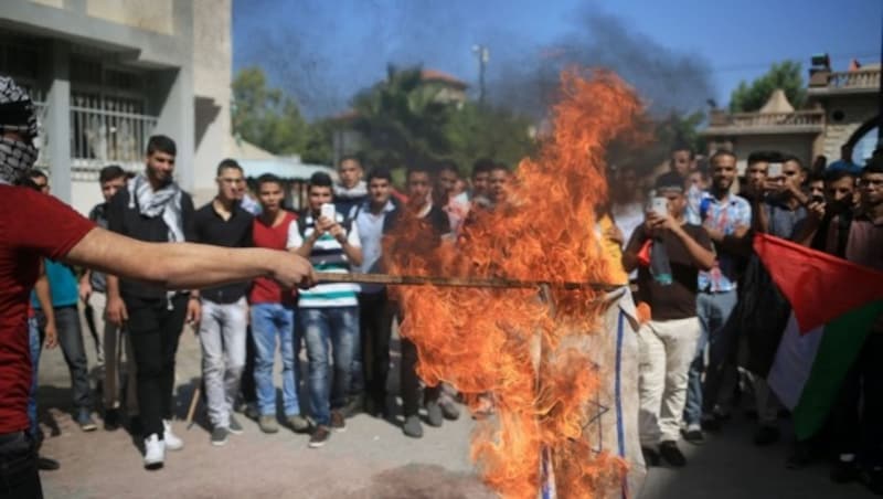 Palästinensische Studenten verbrennen eine israelische Flagge. (Bild: APA/AFP/MOHAMMED ABED)