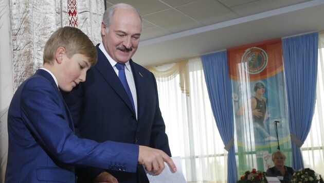 Alexander Lukaschenko mit seinem Sohn Nikolai bei der Stimmabgabe im Wahllokal (Bild: AP)