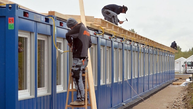 Arbeiter bei der Errichtung eines Containerdorfes in der Salzburger Schwarzenberg-Kaserne (Bild: APA/BARBARA GINDL)