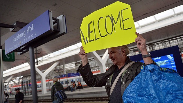 Ein Fahrgast heißt die am Salzburger Bahnhof ankommenden Flüchtlinge willkommen. (Bild: APA/EPA/BARBARA GINDL)