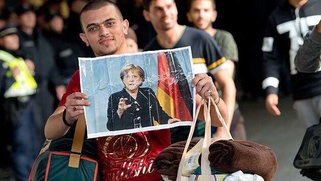 Bahnhof München: ein ankommender Flüchtling mit einem Bild von Kanzlerin Merkel (Bild: APA/EPA/Sven Hoppe)