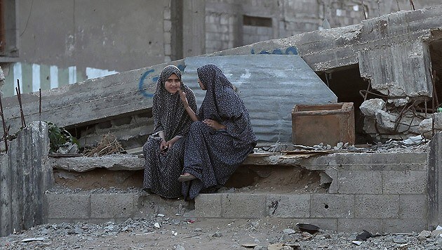 Zwei Palästinenserinnen in einem zerstörten Teil von Gaza-Stadt (Bild: APA/EPA/MOHAMMED SABER)