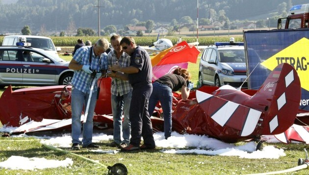 Einsatzkräfte der Polizei untersuchen das abgestürzte Flugzeug. (Bild: APA/GERT EGGENBERGER)