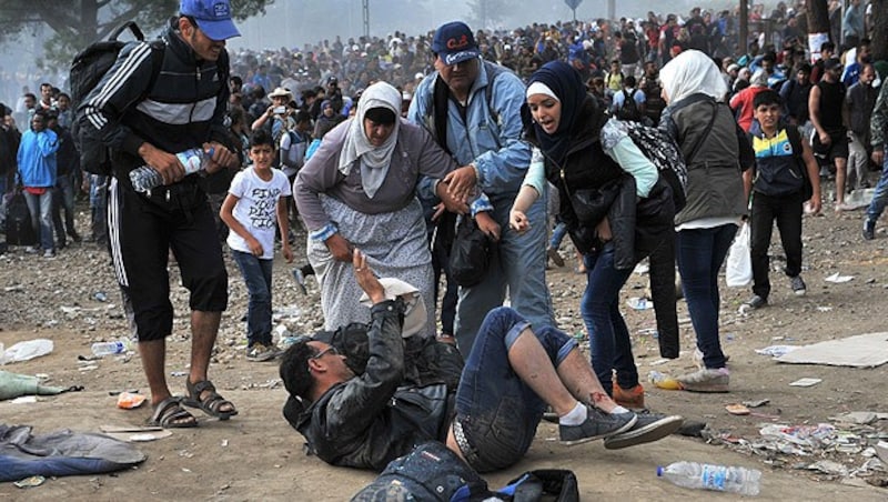 Flüchtlinge kümmern sich um einen Mann, der beim Tränengaseinsatz verletzt wurde. (Bild: AFP)