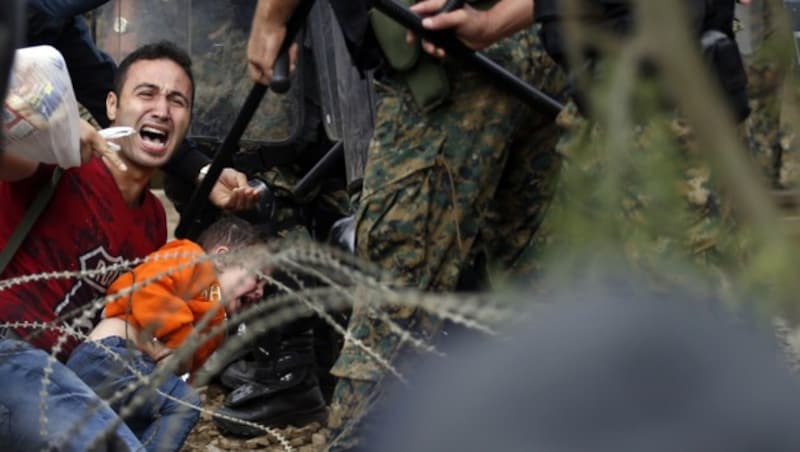 Ein abgedrängter Mann mit einem kleinen Kind schreit verzweifelt um Hilfe. (Bild: AP)