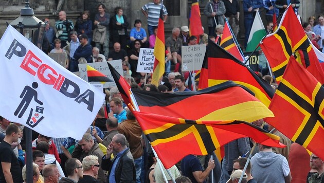 Pegida-Anhänger schwenken die Wirmer-Fahne bei einer Demo. (Bild: APA/EPA/MATTHIAS HIEKEL)