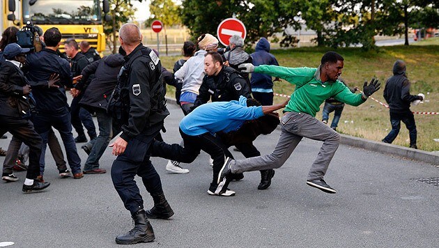 Flüchtlinge versuchen, vor der Polizei zu entkommen und einen Zug nach Großbritannien zu erwischen. (Bild: APA/EPA/YOAN VALAT)