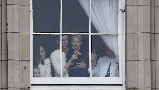Mit seiner Nanny schaut der Mini-Prinz aus einem Fenster des Buckingham-Palastes. (Bild: EPA)