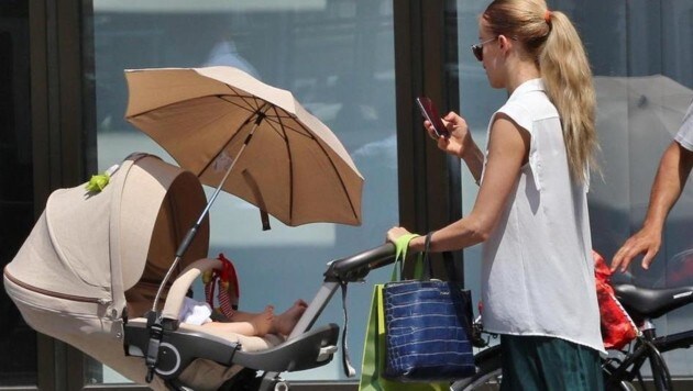 Sarkissova mit Lev im Kinderwagerl, den Blick aufs Handy gerichtet. (Bild: Starpix/A. Tuma/SPY)