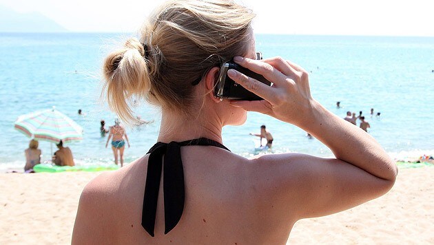 Auch in der Strandtasche ist das Handy meist dabei. (Bild: dpa/Friso Gentsch)