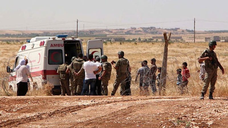 Rettungskräfte helfen nahe Kobane verletzten Kämpfern. (Bild: APA/EPA/STR)