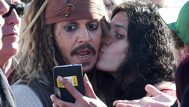 Johnny Depp ließ sich von einem Fan niederknutschen. (Bild: APA/EPA/DAVE HUNT)