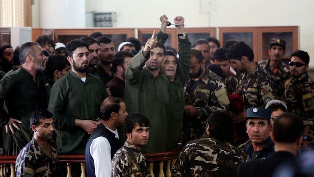 Die Angeklagten werden während des Prozesses von Sicherheitskräften umringt. (Bild: AP)