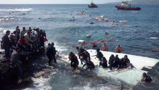 Flüchtlinge werden vom Wrack eines Bootes gerettet, das vor der Insel Rhodos gekentert war. (Bild: EPA/LOUKAS MASTIS)