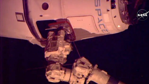 Der Roboterarm "Canadarm2" hält "Dragon" fest. (Bild: NASA TV)