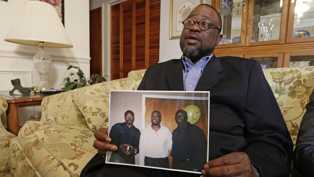 Der Bruder des Getöteten mit einem Familienfoto (Bild: AP)