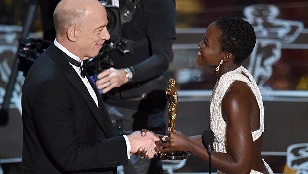 J. K. Simmons übernimmt die Trophäe von Lupita Nyong'o. (Bild: John Shearer/Invision/AP)