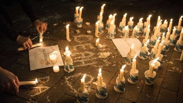 Menschen zündeten Kerzen im Gedenken an die drei muslimischen Mordopfer an. (Bild: AFP)