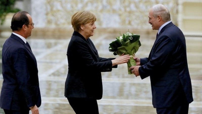 Der weißrussische Autokrat Alexander Lukaschenko, Gastgeber des Gipfels, überreicht Merkel Blumen. (Bild: AP)