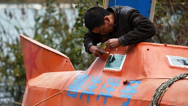 Tan Yong schmiert Dichtungsmasse um ein Bullauge seines U-Bootes. (Bild: AFP)