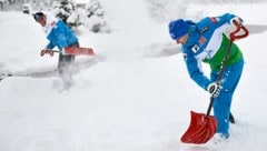 Matthias Mayer (links) and Romed Baumann (rechts) schaufeln in Lake Louis Schnee. (Bild: APA/EPA/Mike Sturk)