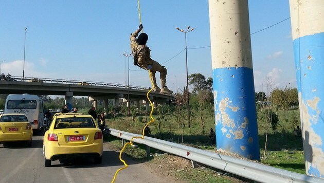Ein IS-Kämpfer seilt sich bei einem Militärtraining von einer Brücke ab. (Bild: APA/EPA/STR)
