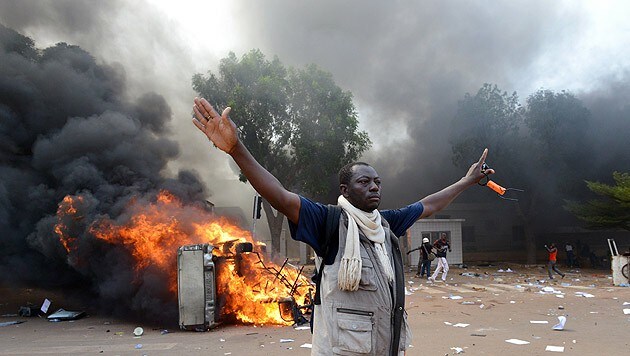 Wütender Demonstrant neben einem brennenden Auto, das in der Nähe des Parlaments geparkt war (Bild: AFP)