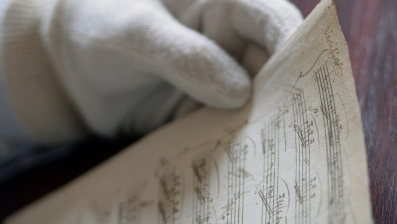 Nur mit Handschuhen fasst Entdecker Balasz Mikusi die neu entdeckten Mozart-Originale an. (Bild: AFP/AFP ATTILA KISBENEDEK)