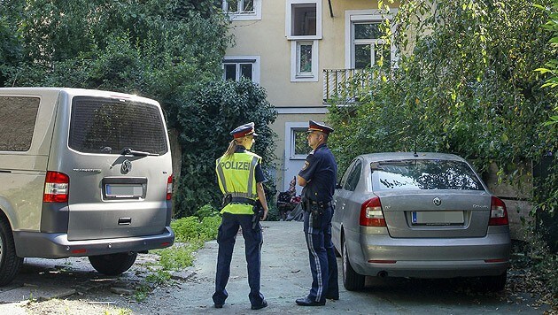Zwei Polizeibeamte vor dem Haus in Graz, in dem die Tat stattgefunden hatte (Bild: APA/ERWIN SCHERIAU)