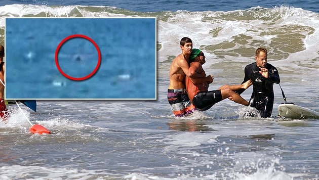 Das Hai-Opfer wird aus dem Wasser getragen. Ein Video zeigt den Angriff am Manhattan Beach. (Bild: AP, YouTube.com)